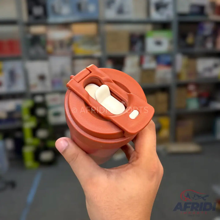 A rust-colored travel mug with a flip-top lid and white drinking spout.