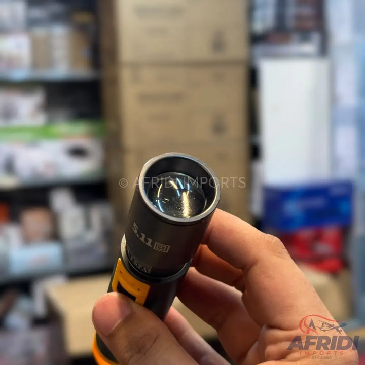 A handheld black and orange flashlight with a clear lens.