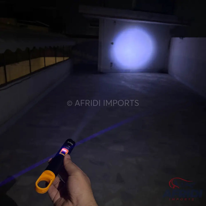 Handheld laser pointer with a purple beam and an orange finger loop.