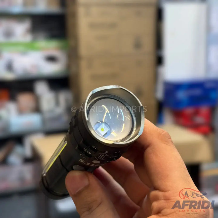 A black tactical flashlight with a bright LED bulb, held in a hand.