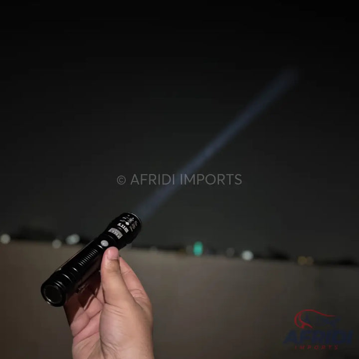 A black, handheld flashlight emitting a bright beam of light.