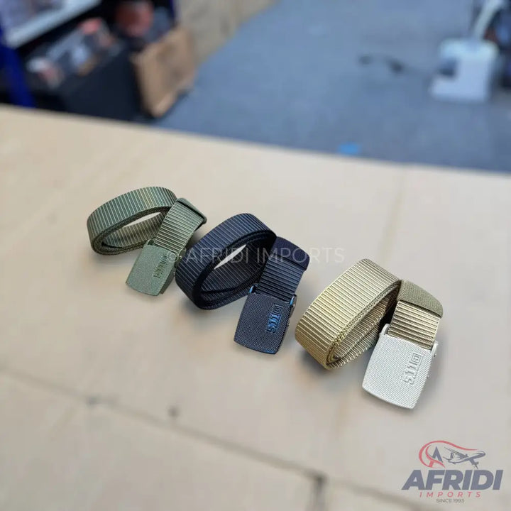 Three coiled tactical belts in olive green, black, and tan.