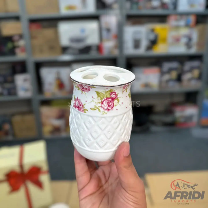White ceramic toothbrush holder with pink and red floral design and a textured diamond pattern.