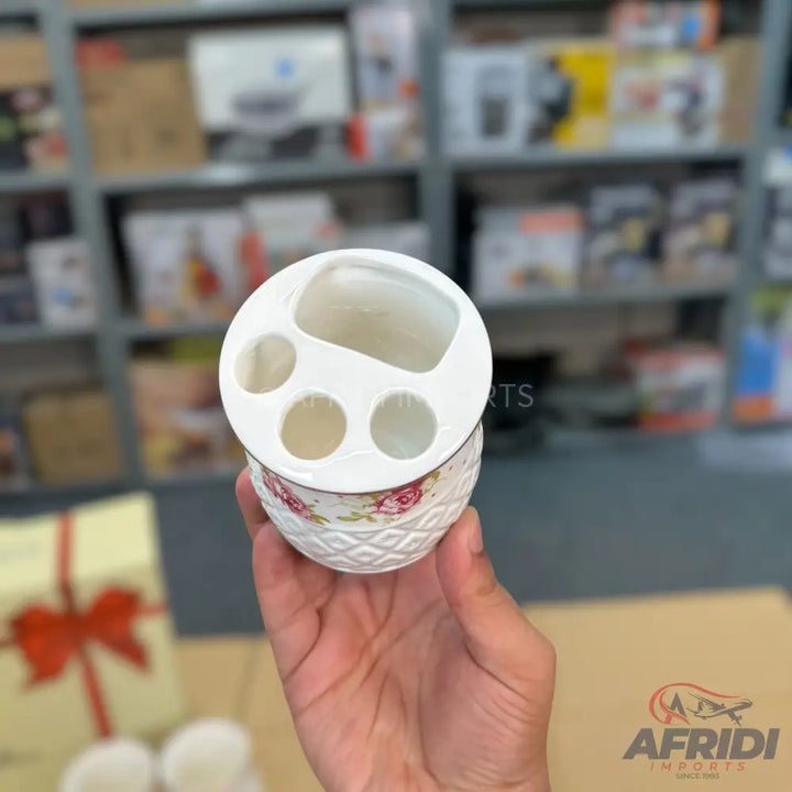 White ceramic toothbrush holder with floral and textured patterns.