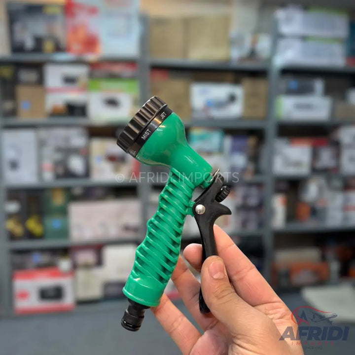 Handheld green spray nozzle with black adjustable head and trigger.