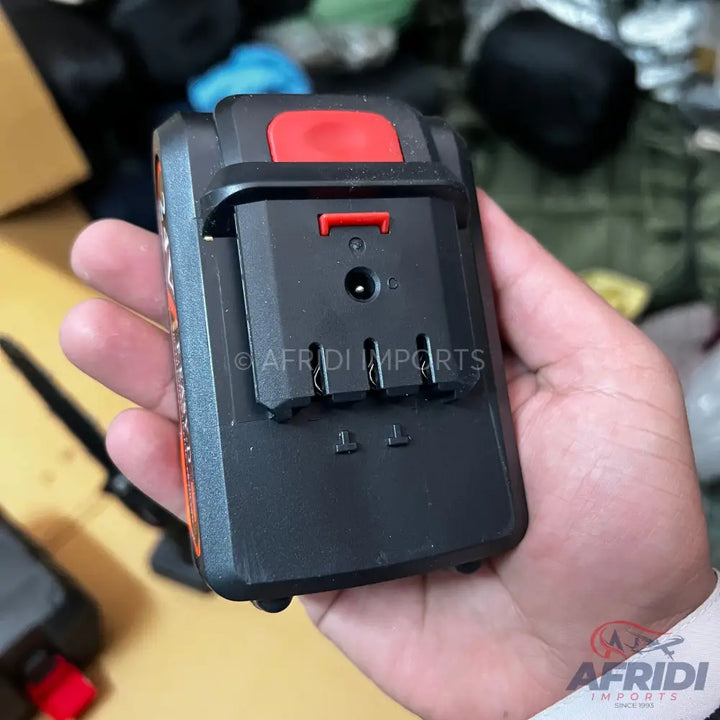 Black and orange power tool battery pack with a red release button and three metal contacts.