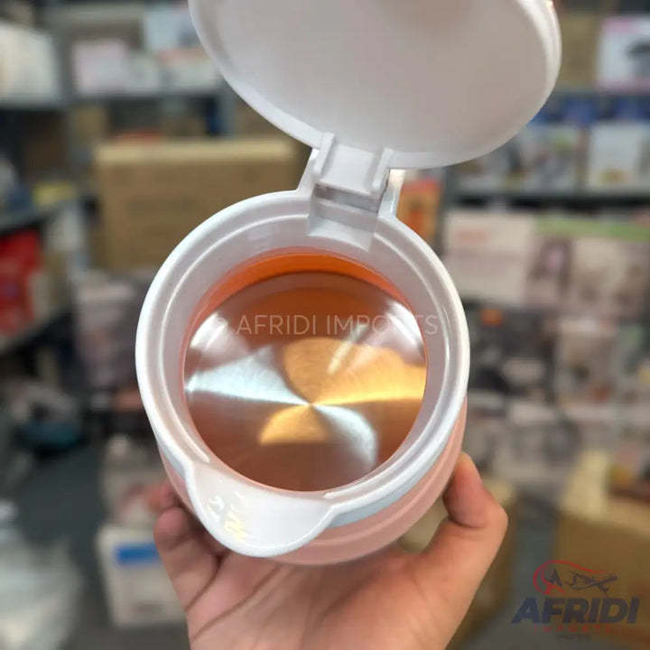 An open, light pink portable electric kettle with an orange interior.