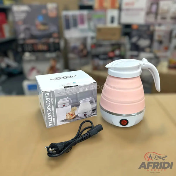 A pink and white collapsible electric travel kettle with a power cord.