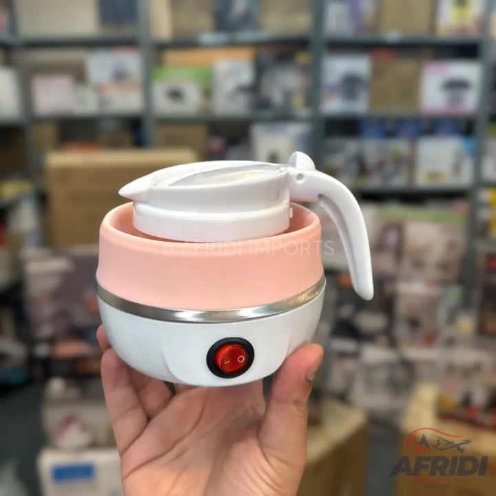 A collapsible pink and white electric kettle with a red power switch.