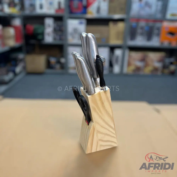 A set of stainless steel knives with black handles in a light wood block.