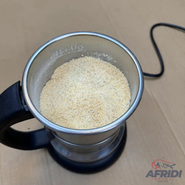 A stainless steel electric grinder filled with light-colored grains.