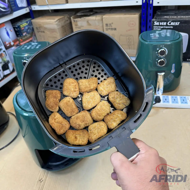 A dark green air fryer with a basket full of cooked chicken nuggets.