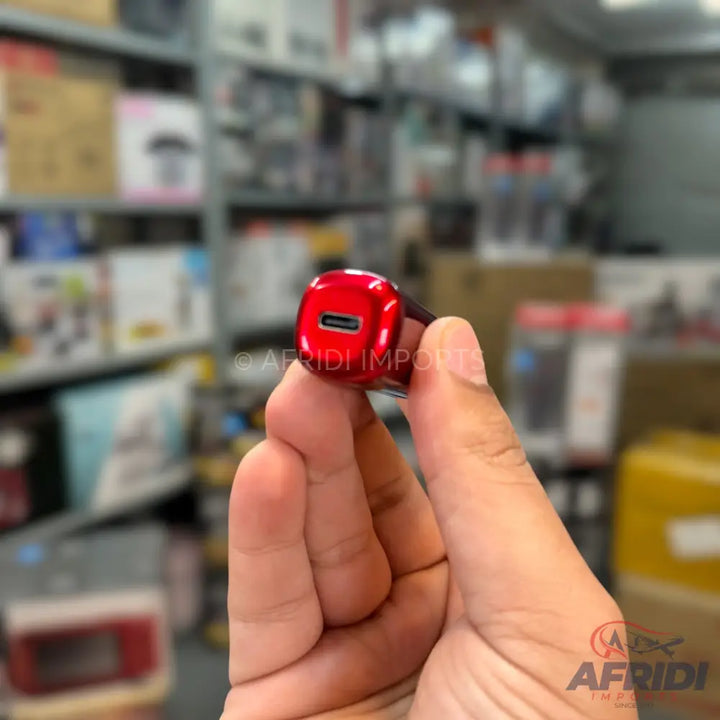 A red, shiny USB-C car charger held in a hand.