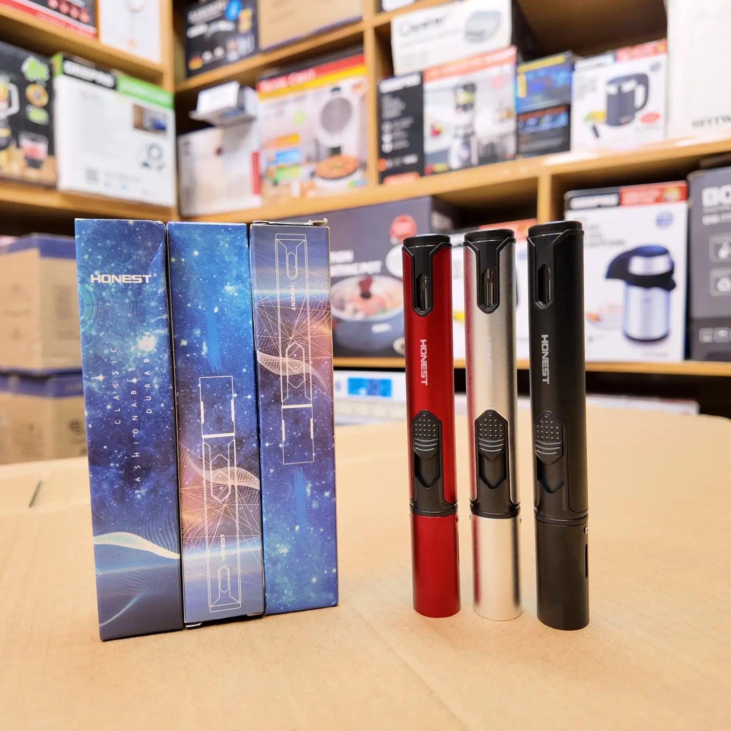 Three cylindrical Lot Imported Honest Jet Flame Lighters in red, silver, black with boxed packaging