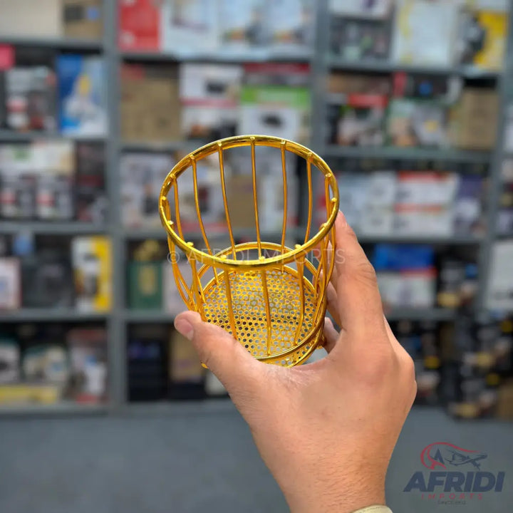 A golden, cylindrical, metal utensil holder or basket with a perforated base.
