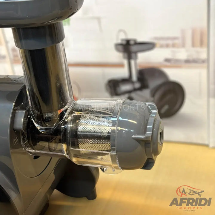 A dark grey and clear plastic juicer attachment with a mesh filter.