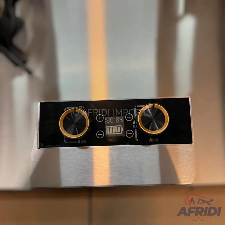 Black rectangular electronic device with two gold-ringed rotary knobs, a digital display, and battery indicator.