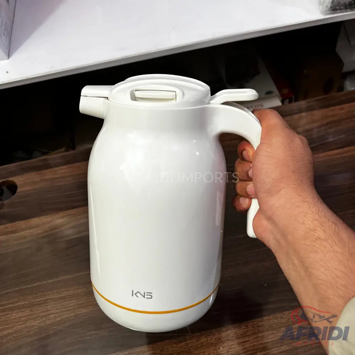 White electric kettle with a handle and a golden band at the base.