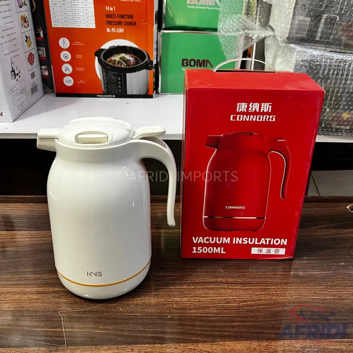 White vacuum insulated thermal carafe with a handle and push-button lid, next to its red retail box featuring a red carafe and text.