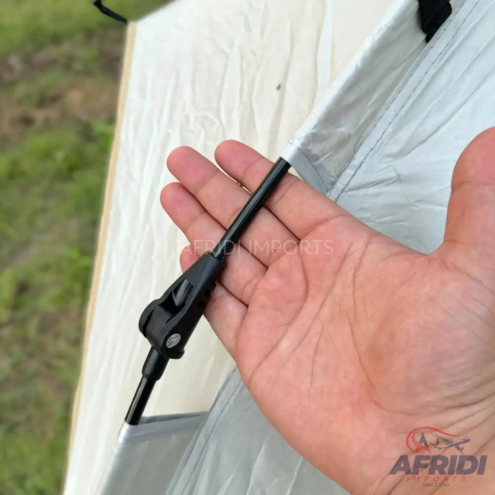 A person’s hand holding a tent pole with a black plastic connector.