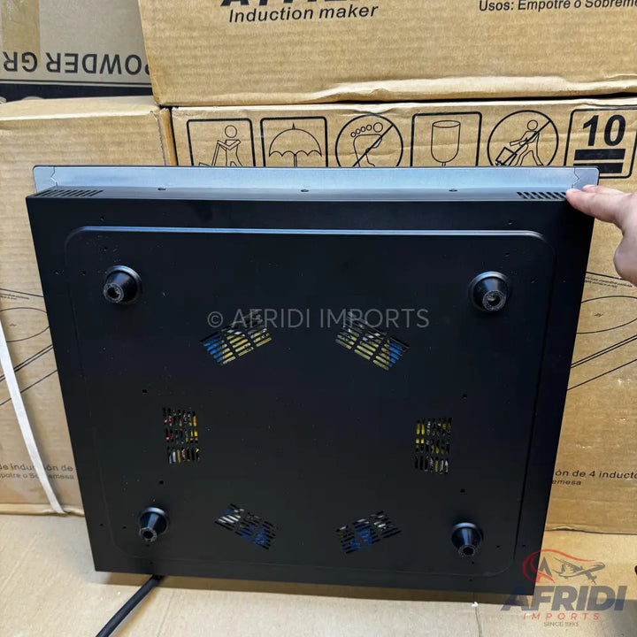 Black induction cooktop with four feet and ventilation grilles on the underside.
