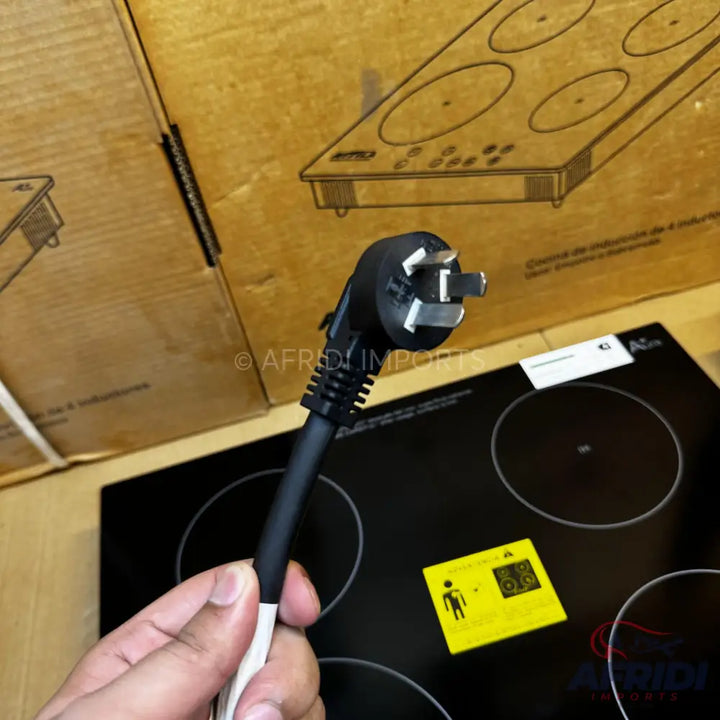 A black four-burner induction cooktop with a Type I power plug.