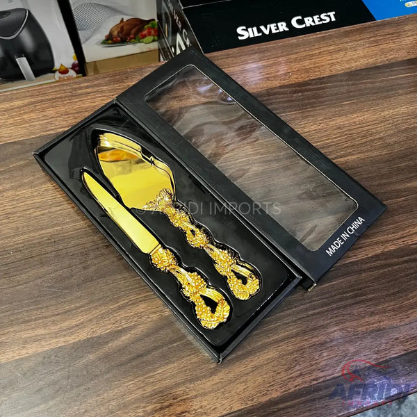 Gold-colored cake serving set with ornate handles, packaged in a black gift box.
