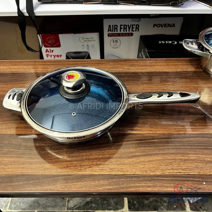 A blue non-stick frying pan with a glass lid and two handles.