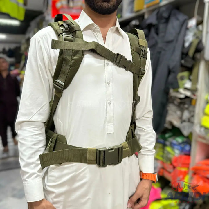An olive green tactical vest or harness with multiple straps and buckles, worn over a white tunic.