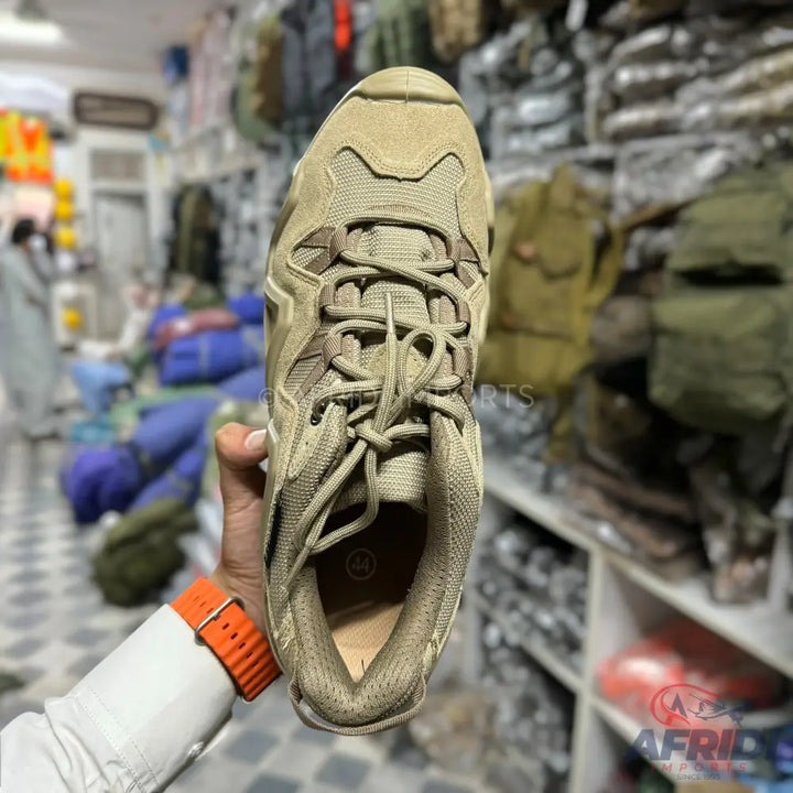A single beige-brown lace-up athletic shoe with a textured mesh upper and a sturdy sole.
