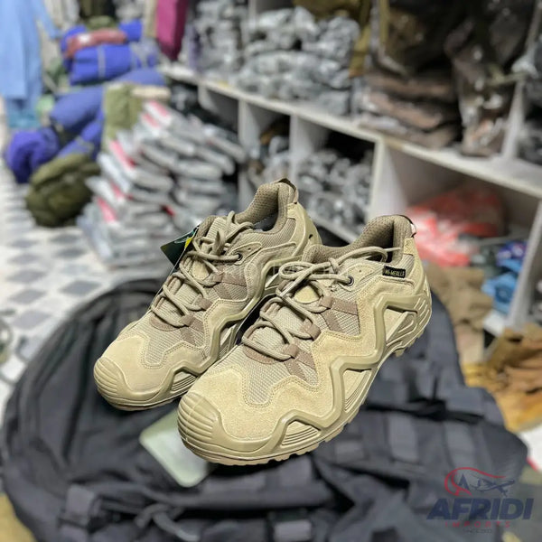 A pair of tan-colored hiking or tactical shoes with intricate lacing and textured soles.