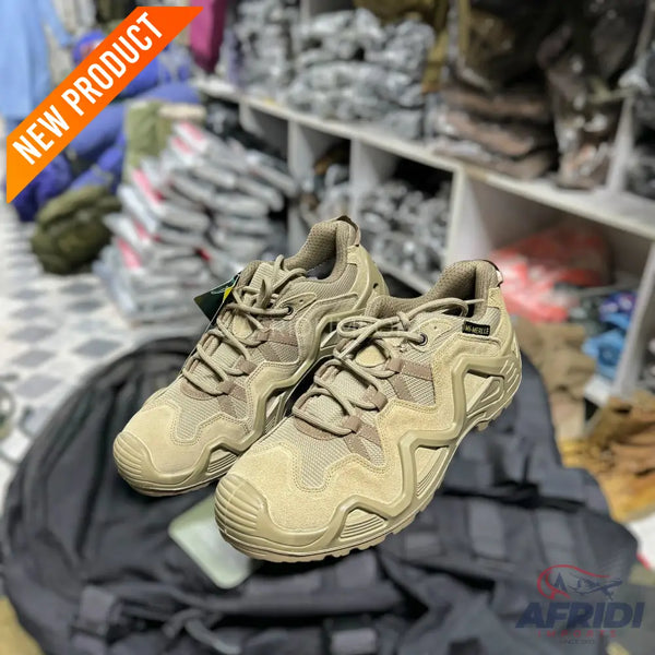 A pair of tan-colored hiking or tactical shoes with intricate lacing and textured soles.