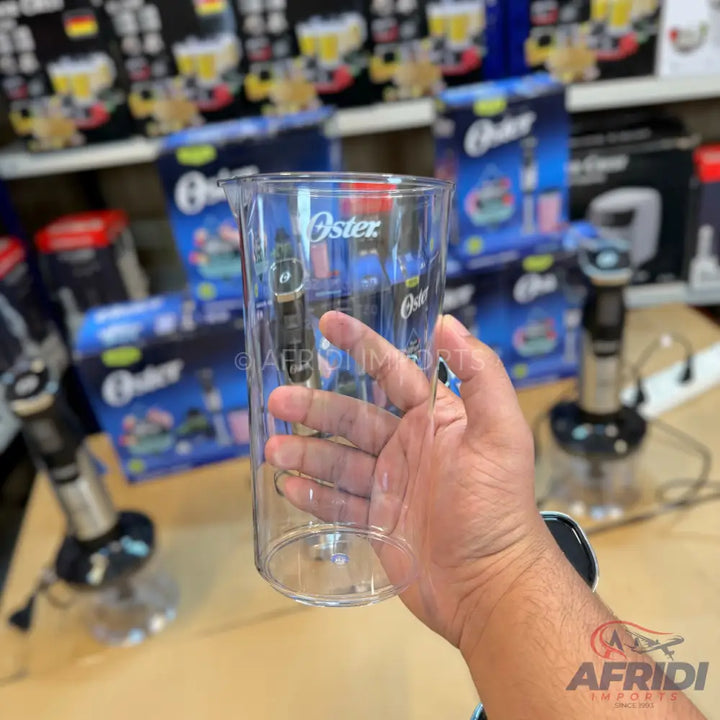 A transparent plastic Oster blender cup with measurement markings.