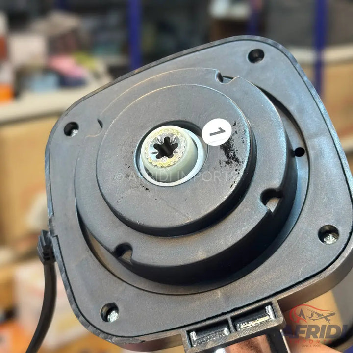 Bottom view of a black car antenna base with a central screw, a cable, and a USB port.