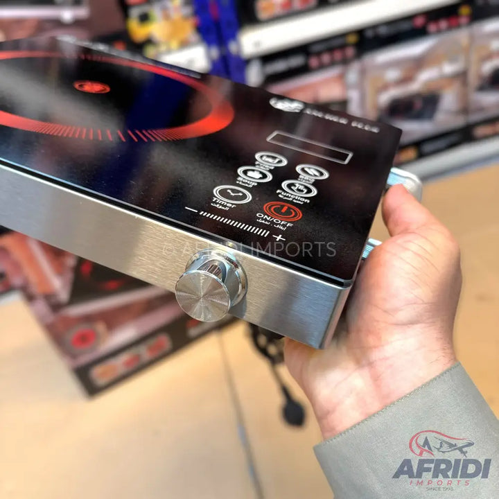 A sleek, portable induction cooktop with a black glass surface, silver trim, and a control panel featuring touch buttons and a rotary knob.