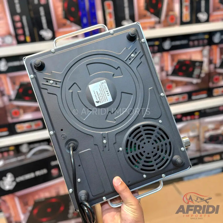 The underside of a portable induction cooktop with a visible power cord, fan, and control knob.