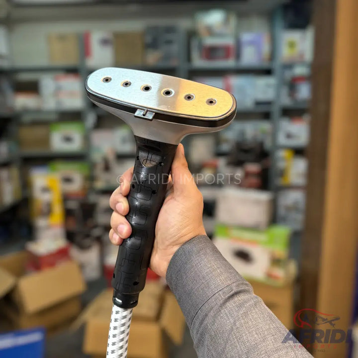 Handheld garment steamer with a metallic-plated head featuring multiple steam holes and a textured black handle.