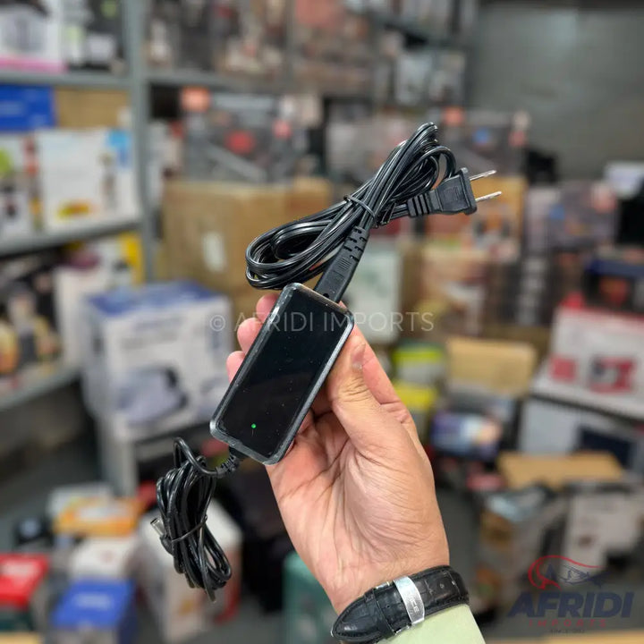 Black rectangular portable device with a connected power cord and a two-prong US-style plug.