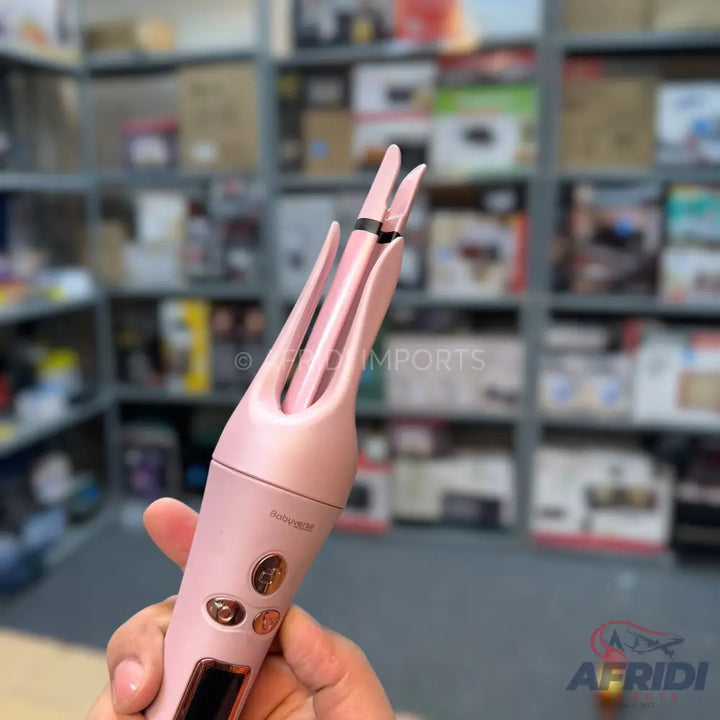 Handheld pink automatic hair curler with control buttons and a digital display.