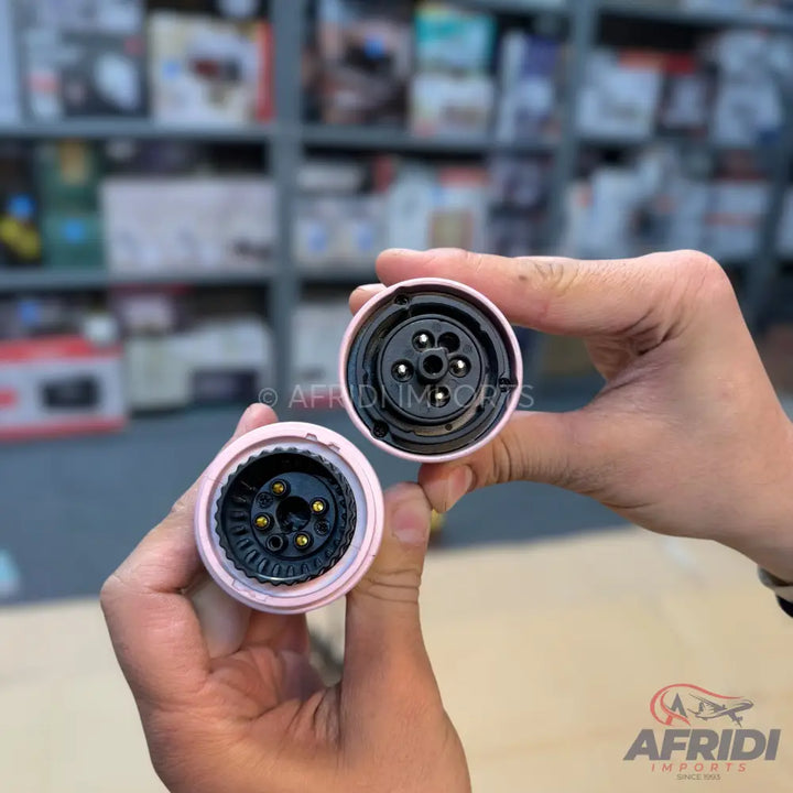 Two pink, circular electrical connectors with five pins each, one male and one female.