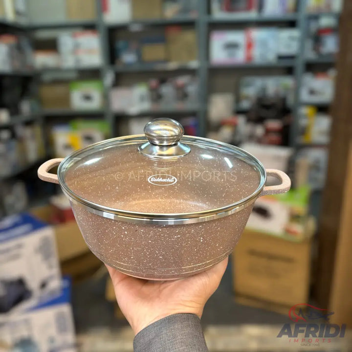 A round, speckled, light brown cooking pot with a clear glass lid and two side handles.