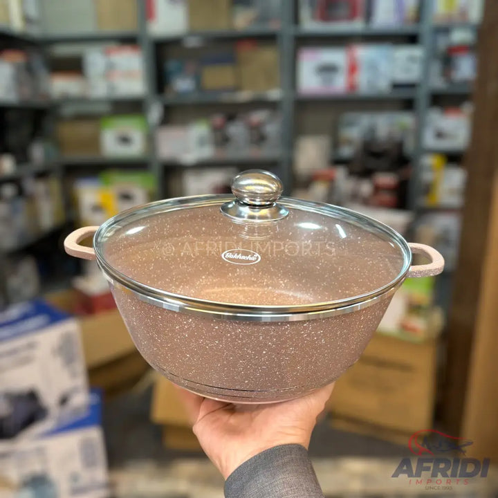 A speckled, light brown, nonstick cooking pot with a glass lid and light pink handles.