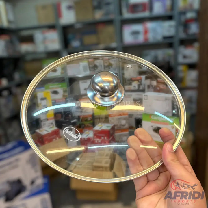 A clear glass pot lid with a metal knob and a gold-colored rim.