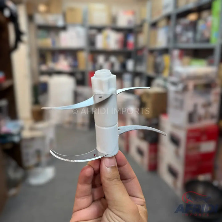 A white plastic food processor blade assembly with four curved metal blades.