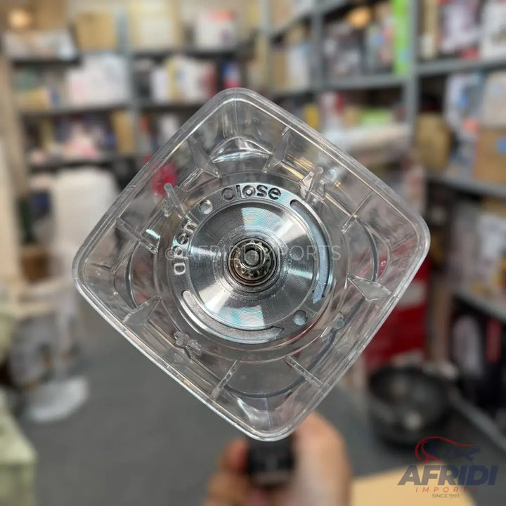 A transparent plastic blender base with a metal coupling, showing ’OPEN’ and ’CLOSE’ indicators.