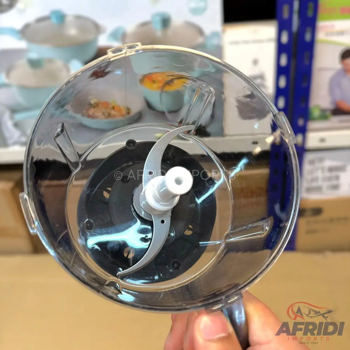 A clear plastic food chopper with a two-bladed rotating mechanism.