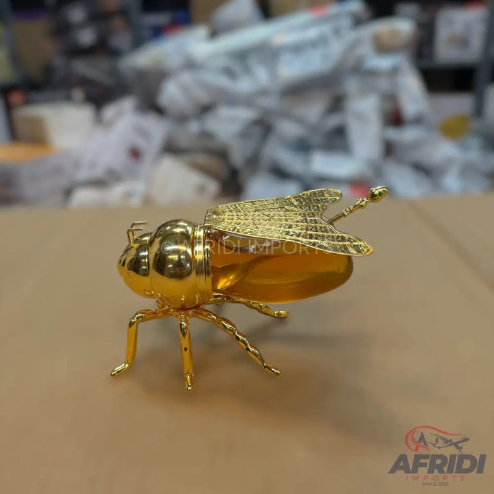 A shiny golden beetle-shaped trinket with textured wings.