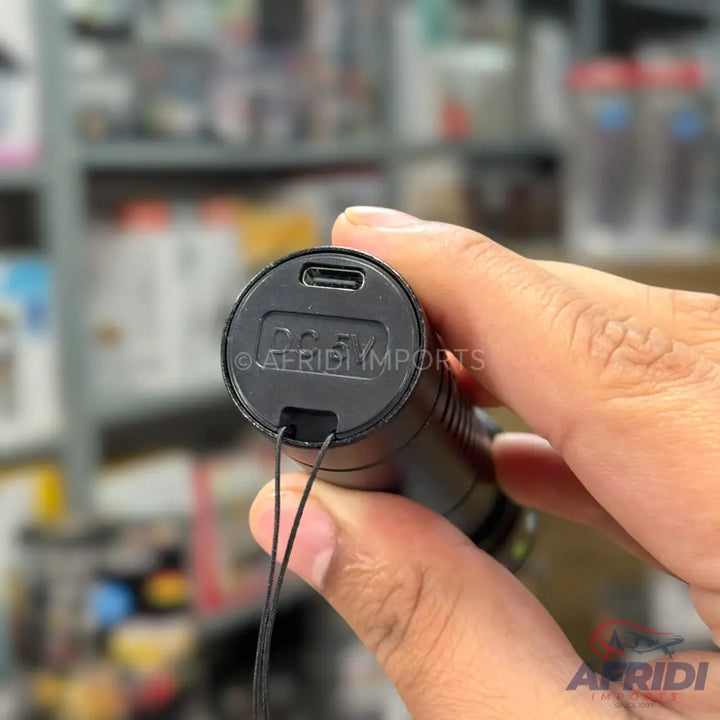 A black cylindrical device with a USB-C charging port and a small loop for a lanyard.