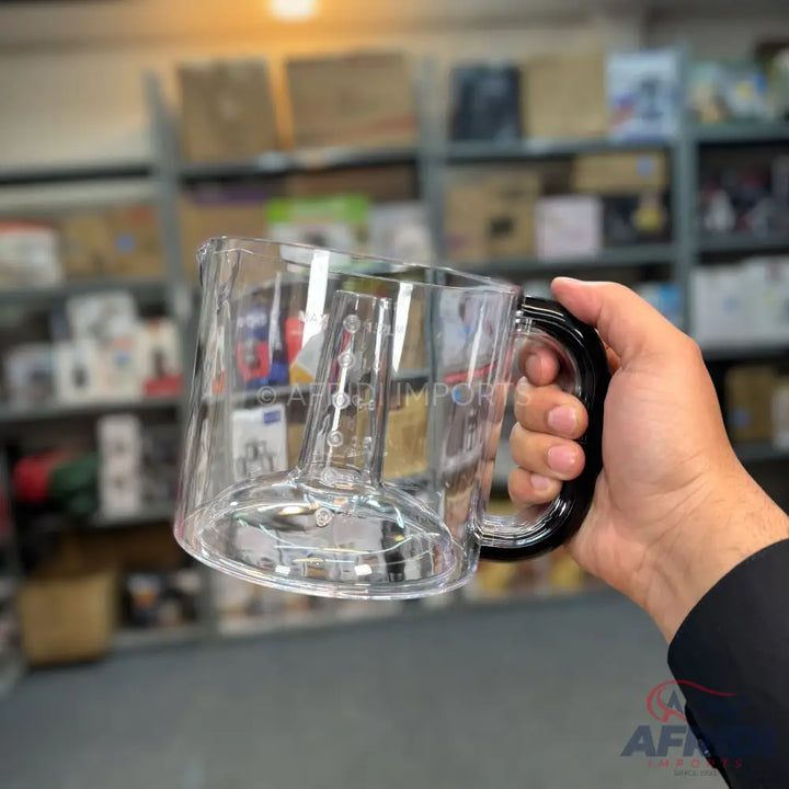 Clear plastic blender pitcher with a black handle.