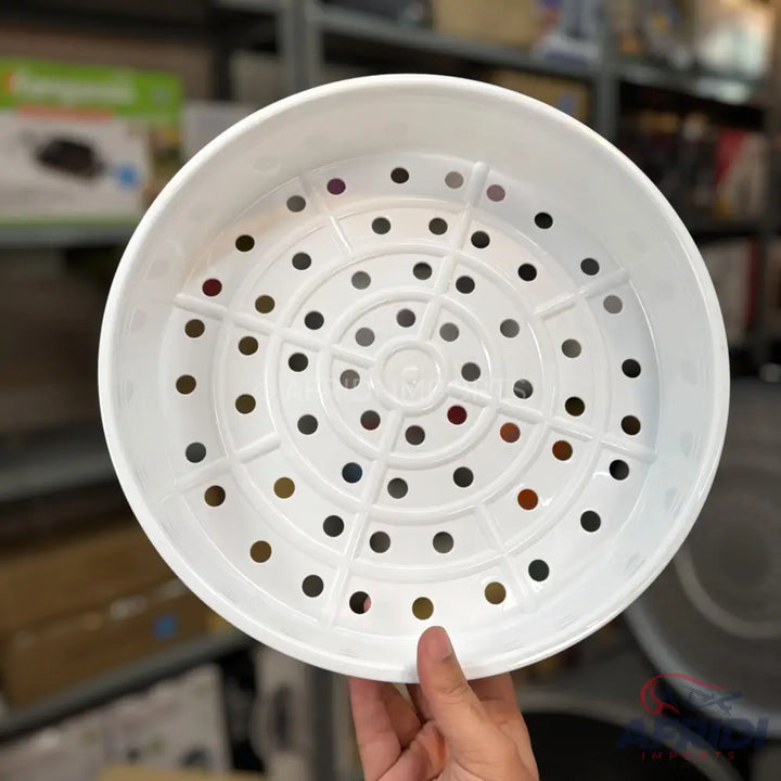 White plastic steamer basket with drainage holes.